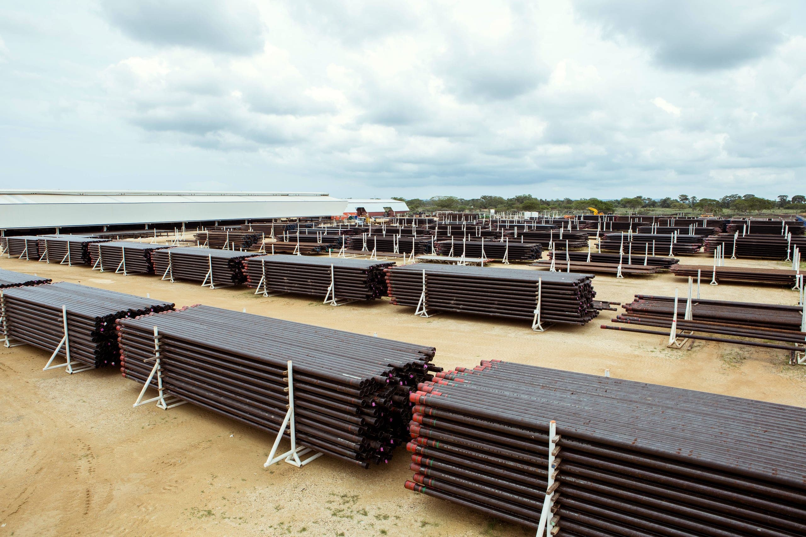 Racked tubulars with red thread protectors, rows leading to the long hall.