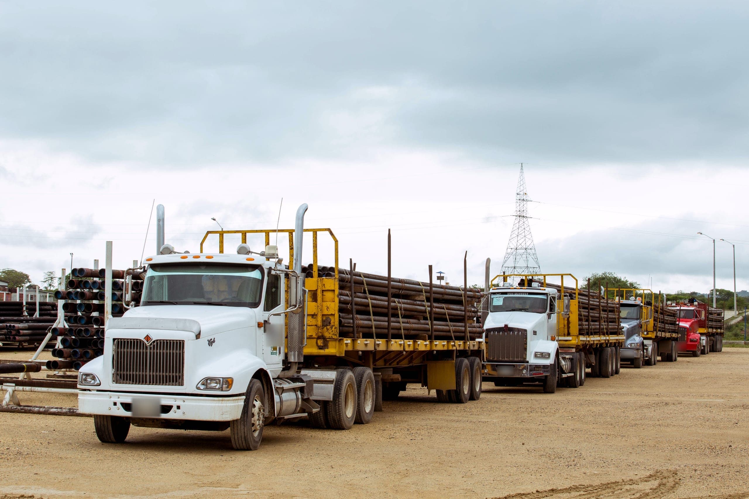Four tractor-trailers loaded with liners, queued in the yard. Plates blurred.