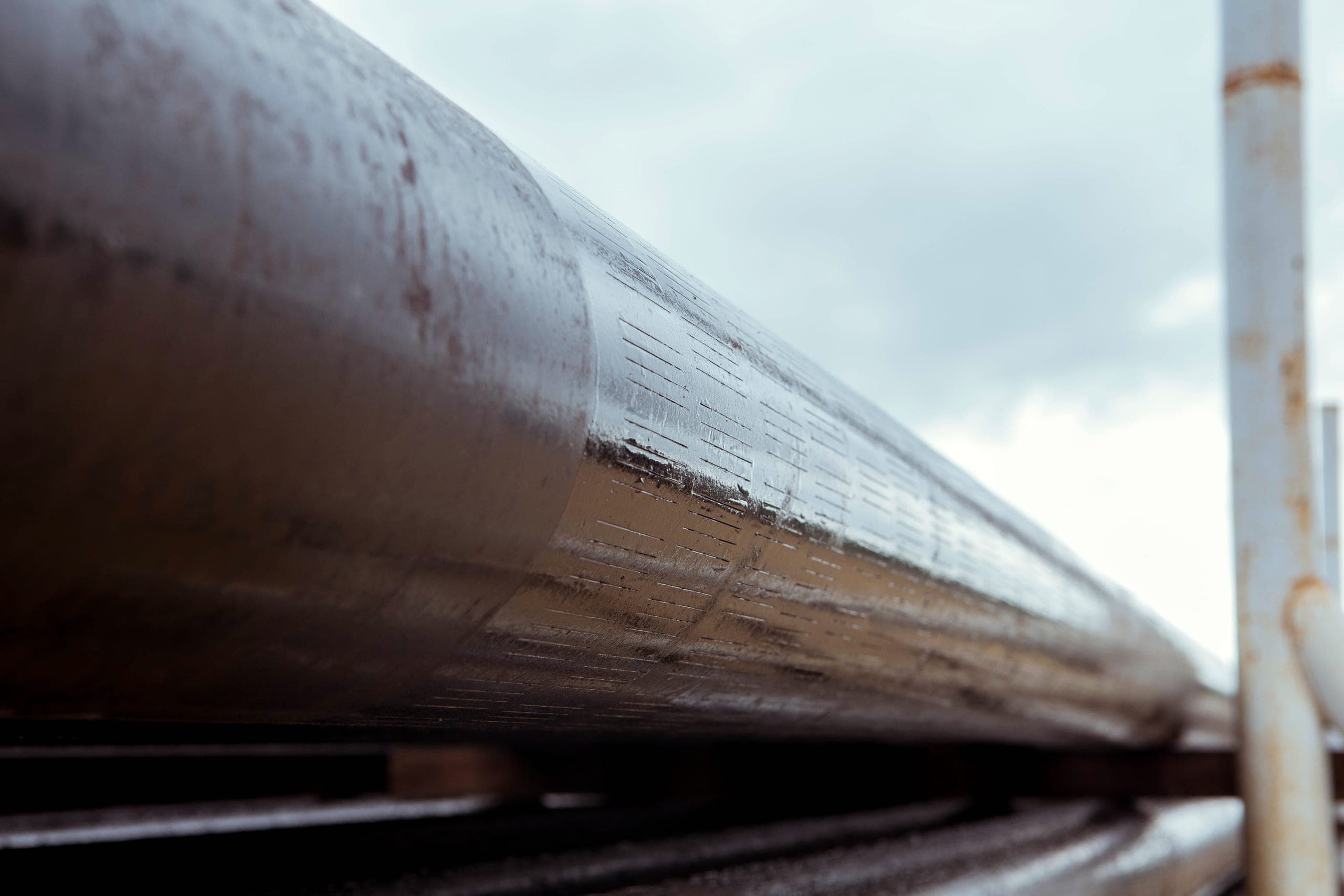 A slotted liner joint on a rack, seen along its length. The slot rows run into the distance.