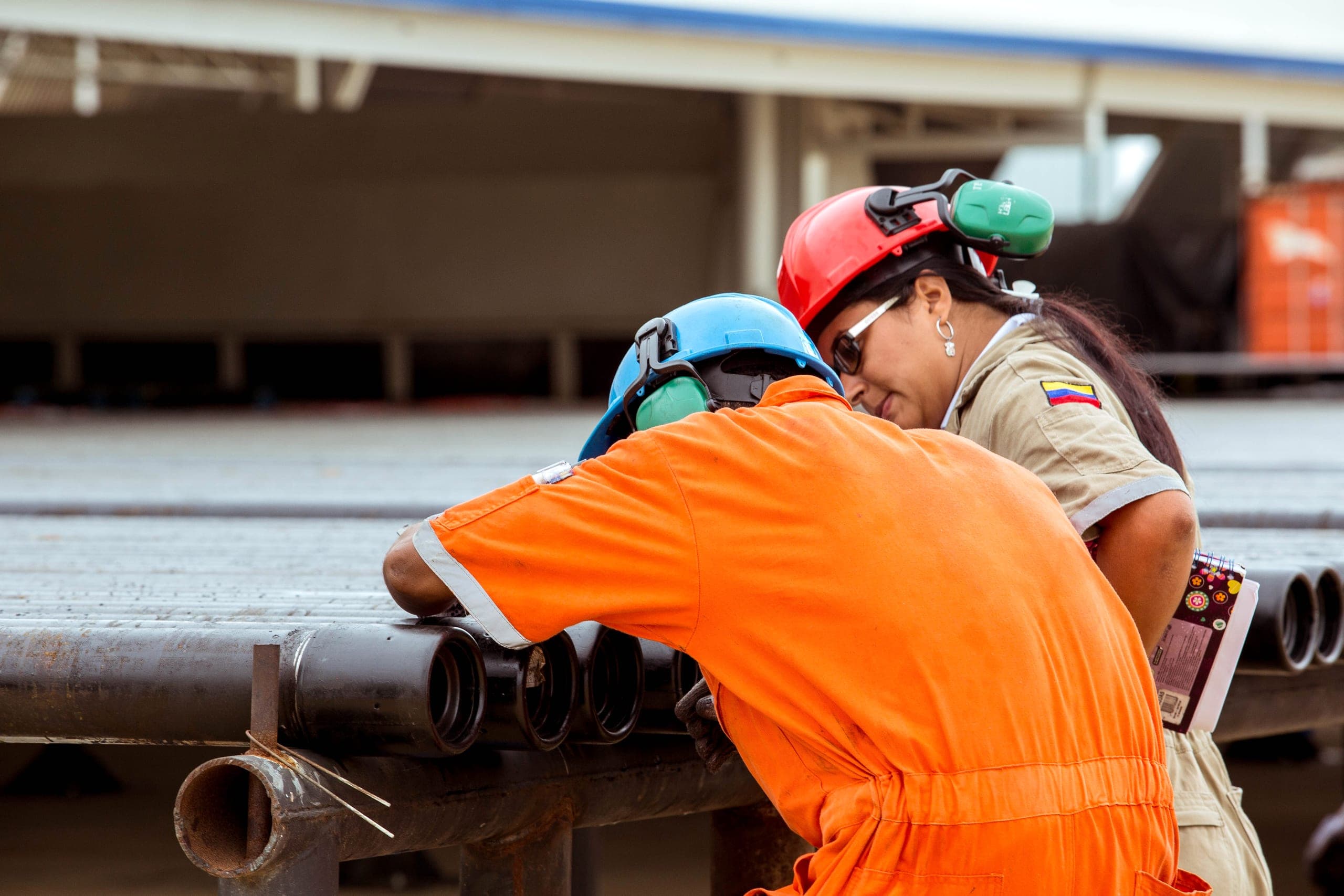 An inspector checks liner ends while a supervisor records the results.