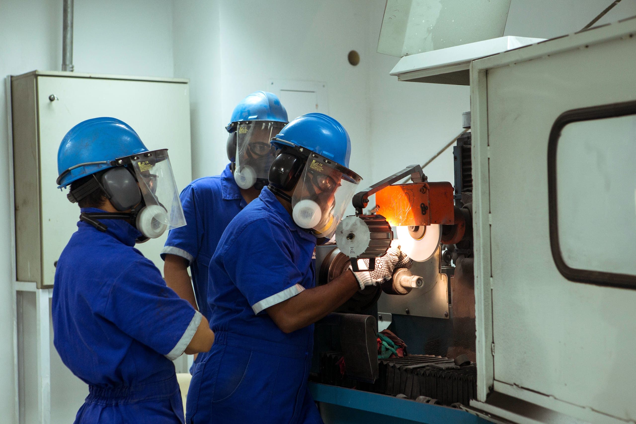 Operators sharpen a slotting saw blade at the grinder.