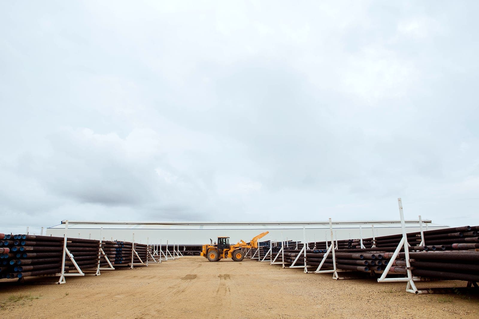 An aisle between long rows of racked liners, a loader at the far end.